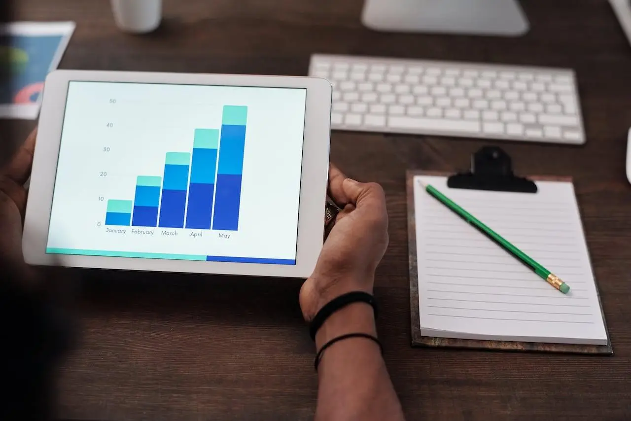 Image of a person holding an iPad with a bar graph displaying analytics to be used for the best youtube strategy.