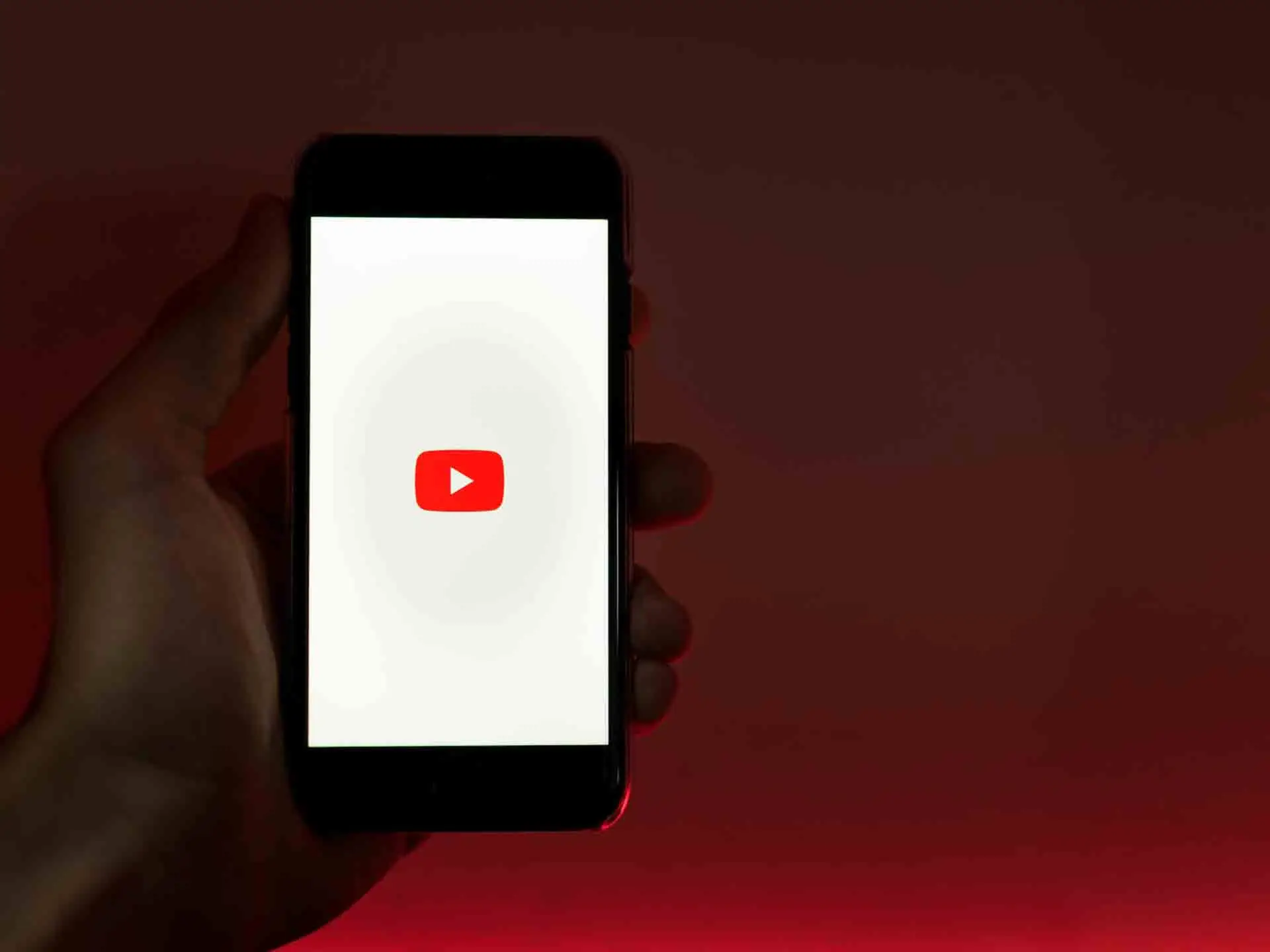 A hand holding a cellphone with YouTube icon on its screen.