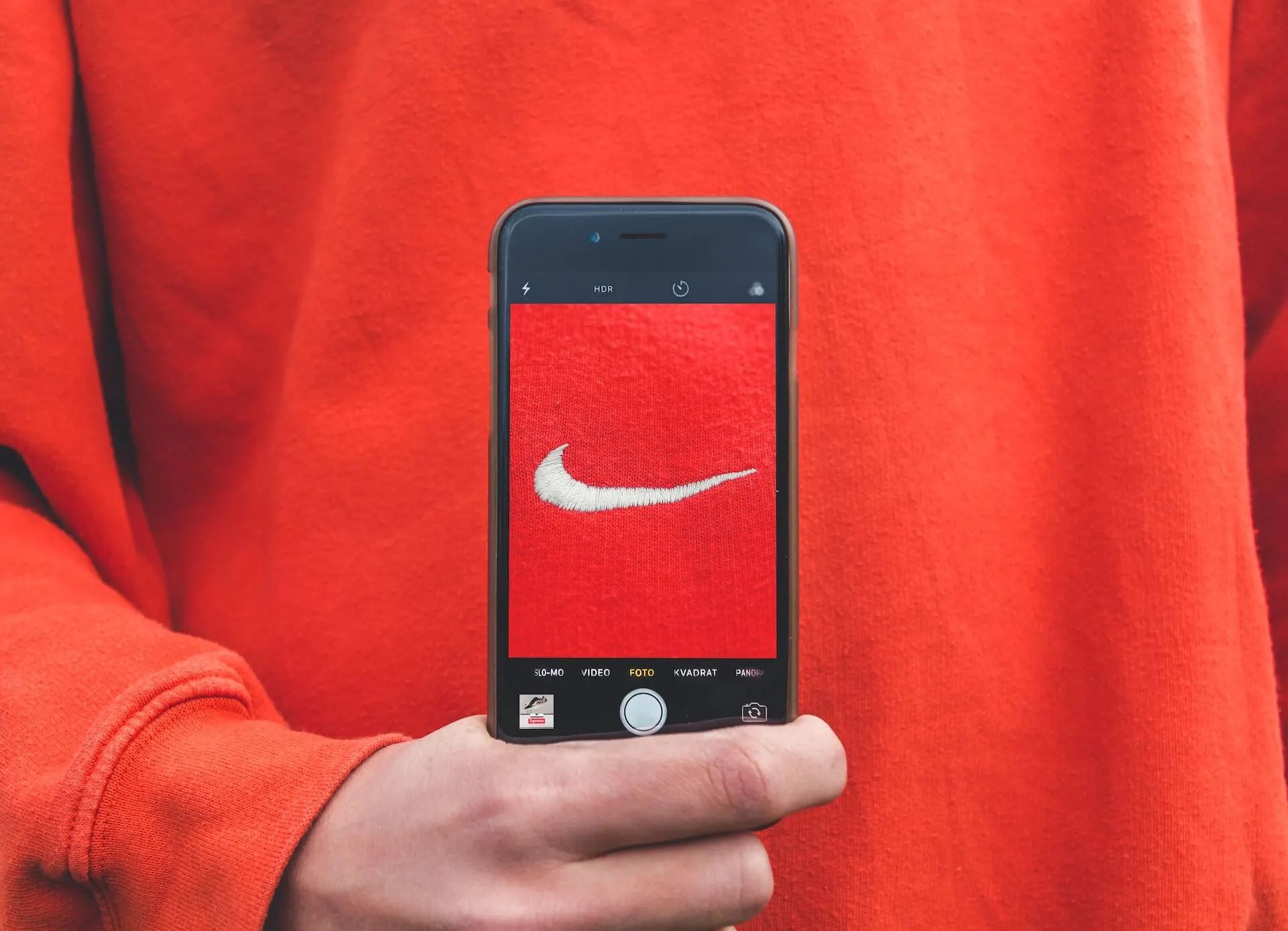 Man holding a mobile phone with the Nike swoosh logo