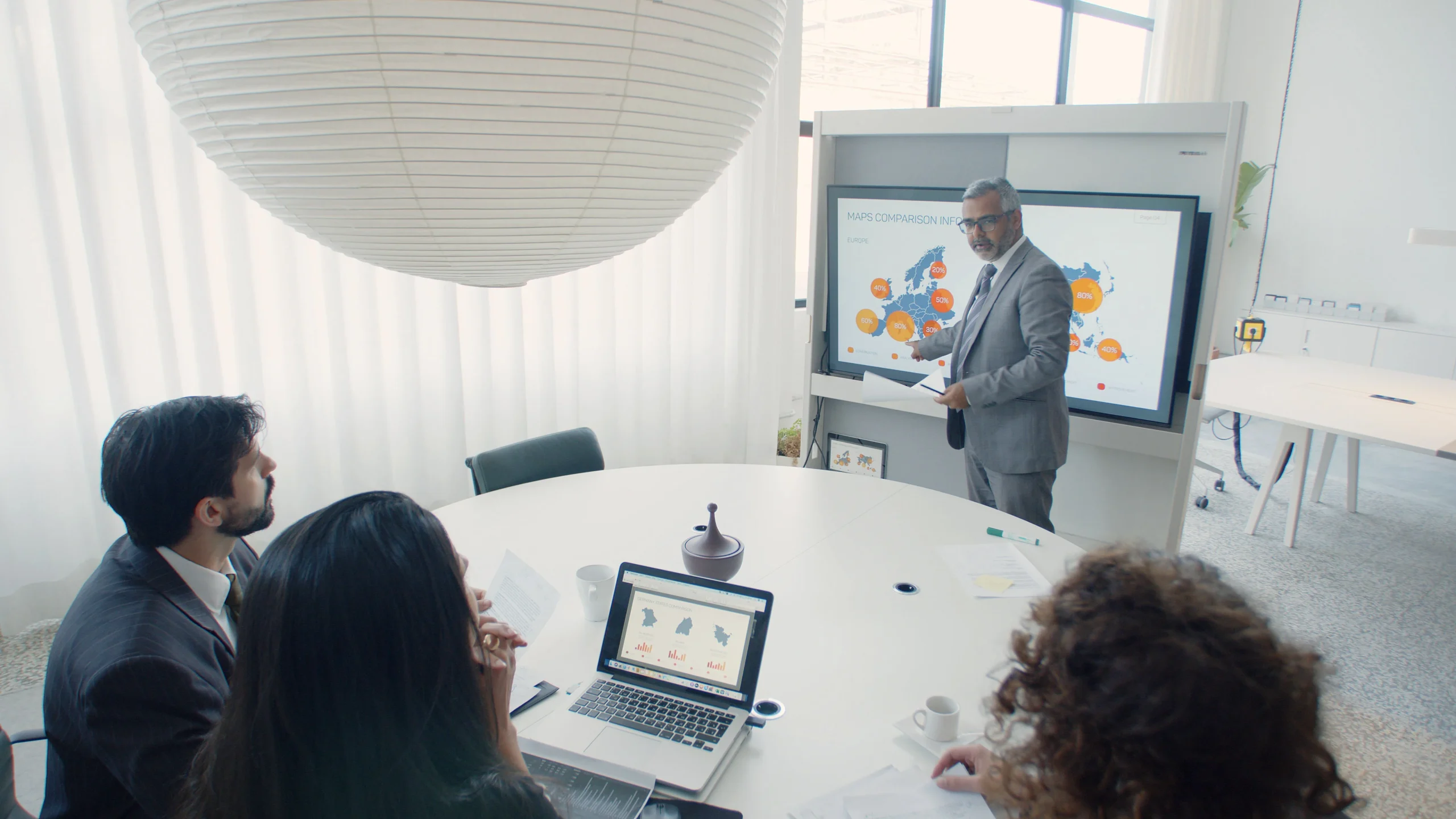 A CMO or marketing executive presenting global brand analytics on a digital display board to a team during a strategy meeting.
