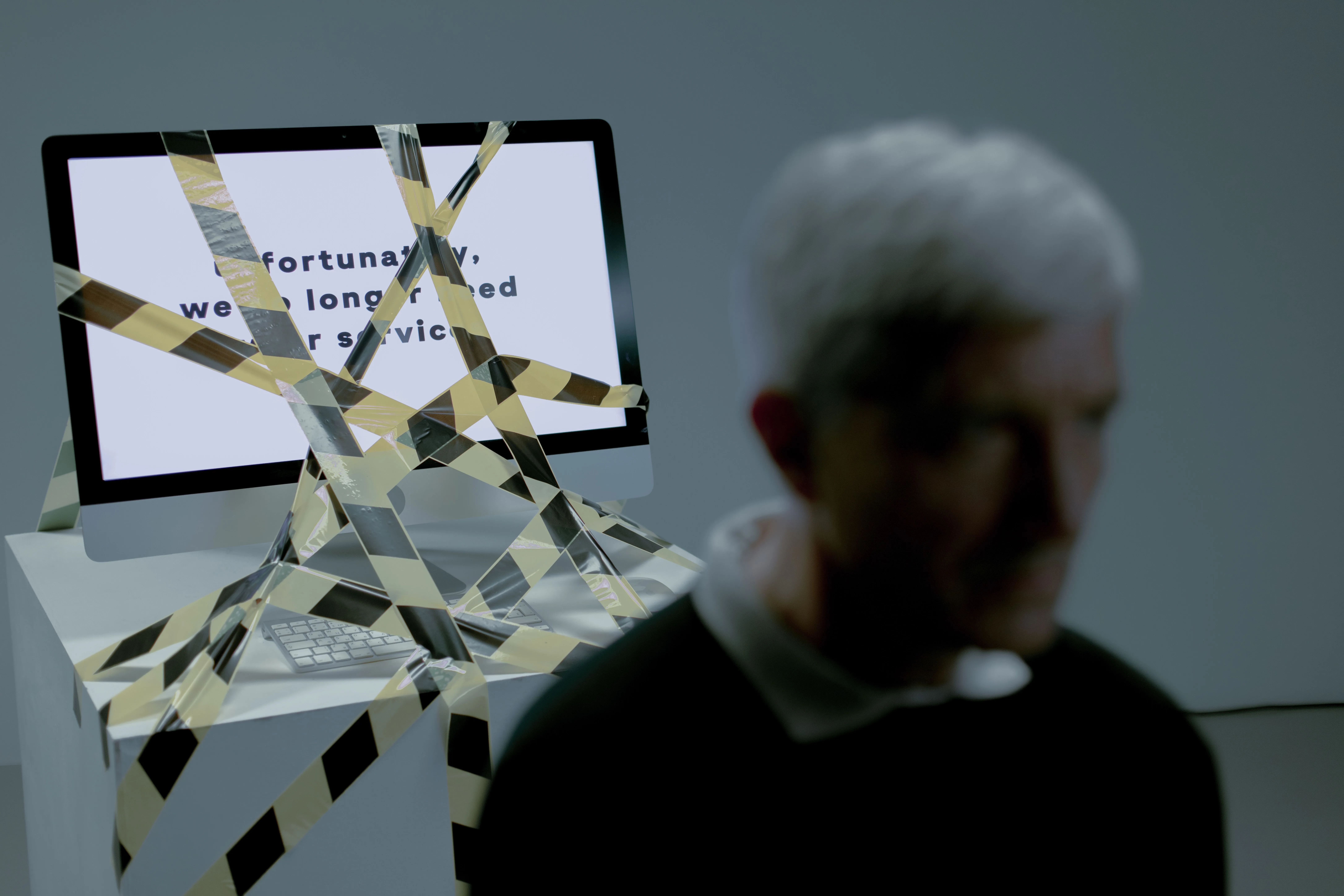 Desktop computer screen wrapped in caution tape with a layoff message.