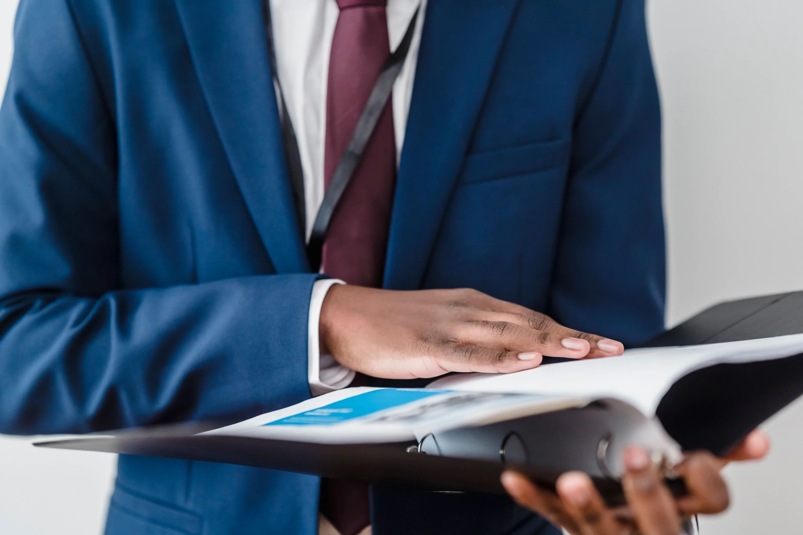 A professional in a blue business suit reviewing a corporate binder during a content partner evaluation process