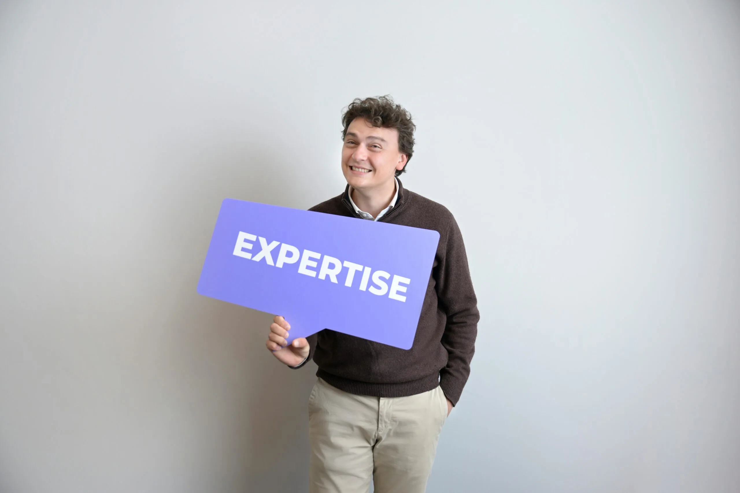 Man holding purple speech bubble sign reading Expertise